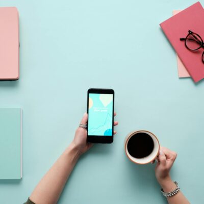 Person Holding a Smartphone and a Cup of Coffee